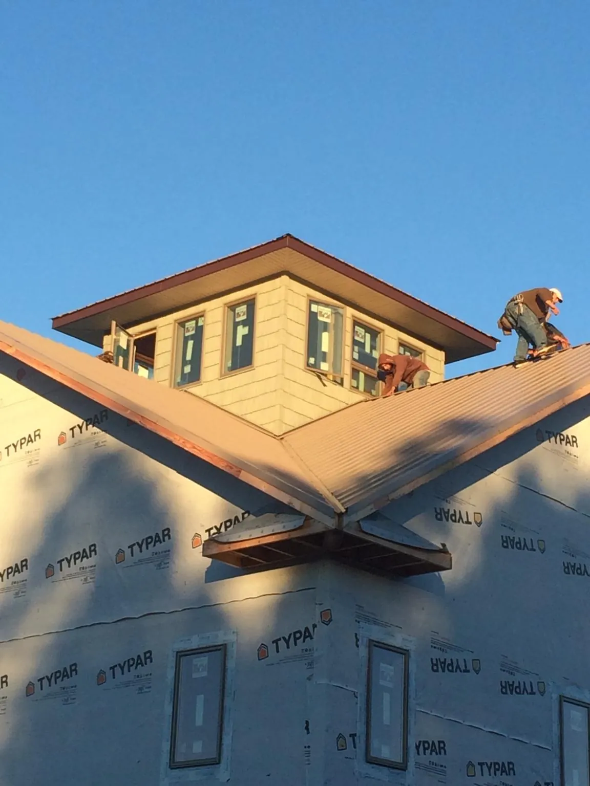 Roofers working around a rooftop cupola on a new metal roof at sunset — Roof Waterproofing in Wynnewood by Roofing Brothers